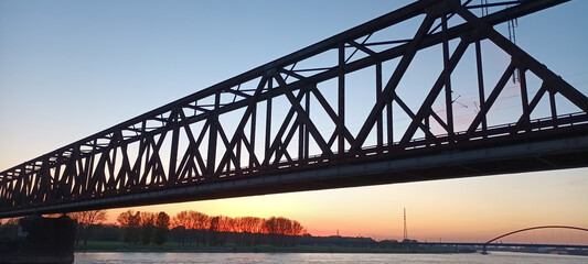 Rhein und historische Eisenbahnbrücke in Duisburg Hochfeld bei Sonnenuntergang