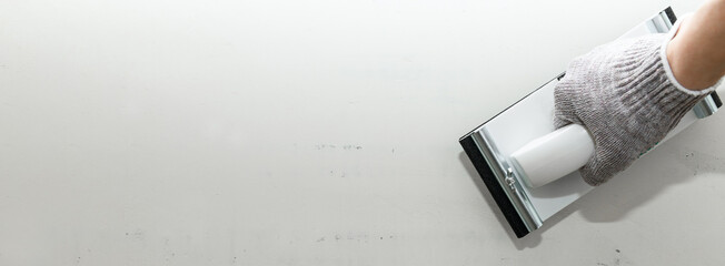 Plaster float in male hand in glove against a gray wall. Plastering grater in the hands of a...