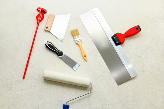 Paint set: roller, brush, spatulas, whisk for plaster on the concrete floor, close-up. Repair tools lies on floor