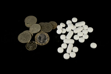 bulgarian lev coins and white pills on a black background from up close