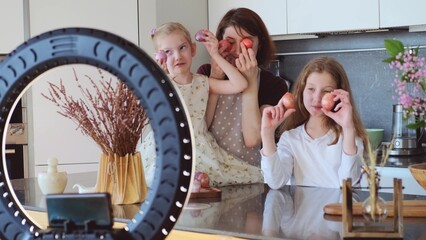 Fototapeta na wymiar Easter. Mom and two cute daughters are preparing at home for the traditional spring holiday. The family makes a video, a guide for dyeing Easter eggs.