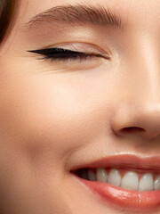 Obraz premium Half beauty portriet woman smiling at the camera with a snow-white smooth. Beautiful natural makeup, puffy lips, smooth and thick eyebrows, extremely long eyelashes. Clean fresh skin
