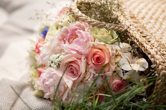 Delicate bouquet in a straw basket. A basket on a blanket outside. Wedding bouquet.