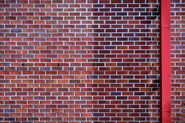 Red brick wall with white cement and red gutter pipe