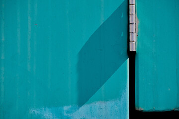Abstract of turquoise, exterior metal door with chrome hinge