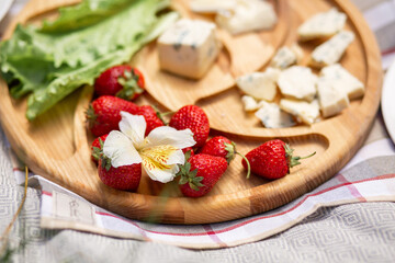 Strawberries on a cheese plate. Outdoor picnic.