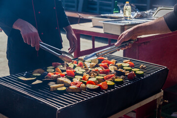 Chefs cook vegetables on the grill - zucchini, potatoes, mushrooms, eggplant.