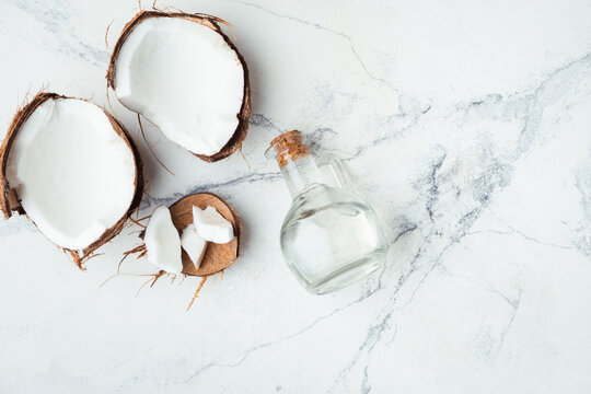 Cracked coconut with coconut oil in glass bottle on the white background