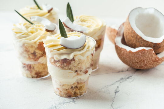 English layered dessert trifle of buscuit dough, custard and whipped cream with fresh coconut pieces on the white background
