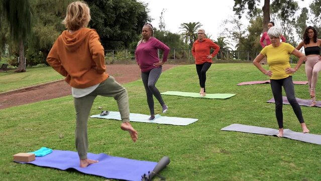 Multiracial people doing yoga class at city park