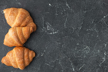 Close up shot of a bunch of homemade croissants on a dark background.