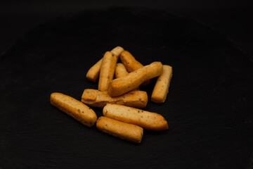 Grissini lying on a plate on a black background