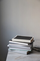 There is a stack of books on a beige table against a white wall. Scandinavian style. Minimalism. Place for text