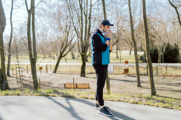 A man with a pollen allergy stands outside in a park. An athlete stops running practice due to a...