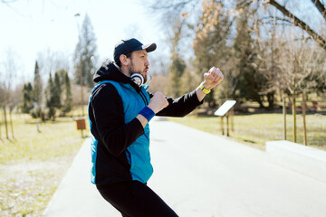 Young sporty strong athletic toned fit sportsman male 30s in sports clothes warm up boxing training fist fight look ahead, spring morning in public park, sunny day.