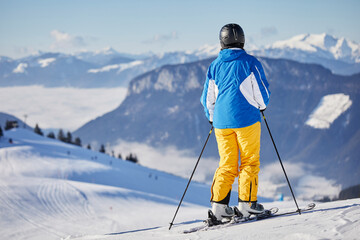 the skier is preparing for the descent against the backdrop of the beautiful mountains of the Alps