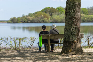 Fototapeta na wymiar Older couple looking at the lake in the shade. Woman on the jetty. Aureilhan pond. Mimizan. Landes
