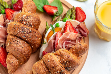 Delicious fresh breakfast served grilled bun with spinach and cheese, asparagus, jamon, ham, prosciutto and fried egg. fresh juice, Balanced diet. place for text, top view