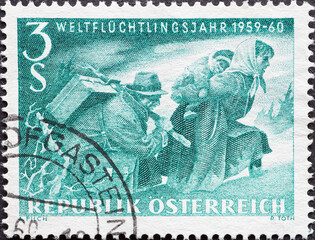 Austria - circa 1960: a postage stamp from Austria, showing a refugee couple with a child and suitcase escaping. World Refugee Year