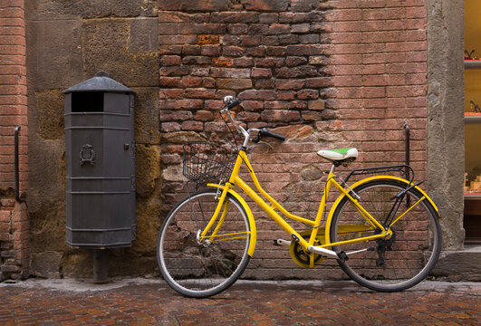 Old, yellow vintage bicycle against a textured, brick wall in Lucca, Italy
 - Powered by Adobe