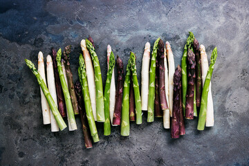 Green, white and purple asparagus on a kitchen background - 500455901