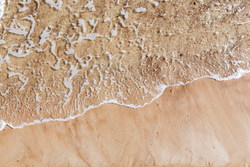 Sea shore with sand and foam, top view. Abstract background photo