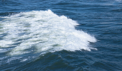 Wave with white foam goes on blue sea water, background photo