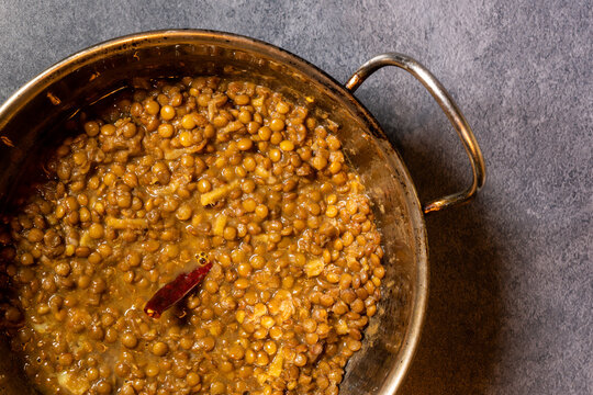 Homemade spicy brown lentil or masoor dal soup with chilli in a wok. Indian brown lentil curry.