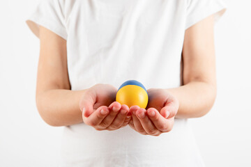 Little girl holding easter eggs on blue and yellow background.