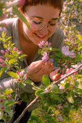 Beautiful young woman enjoying the beauty of blooming apple trees in springtime in South Tyrol,...
