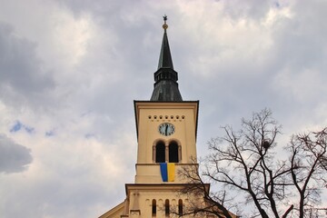 Fototapeta na wymiar A tower of the evangelic church with the flag of Ukraine at Nosislav, Czech republic 