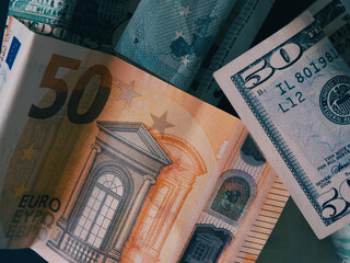 Paper banknotes in denominations of 50 dollars and 50 euros, a close-up shot.