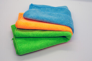 Isolated soft, fluffy, clean folded multiple colorful towel on white background, blue, orange, green fabric towel