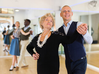 Elderly woman learning ballroom dancing movements in pair
