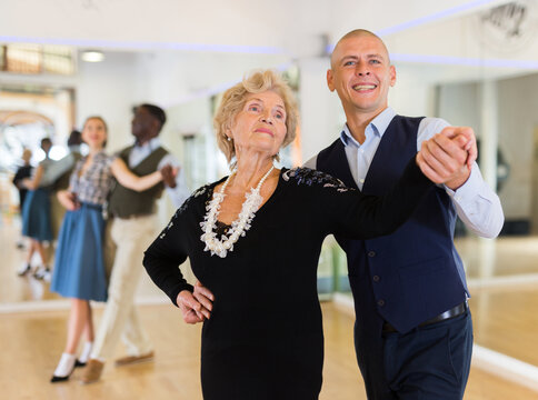 Elderly woman learning ballroom dancing movements in pair