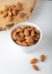 Almonds in white bowl on white background.