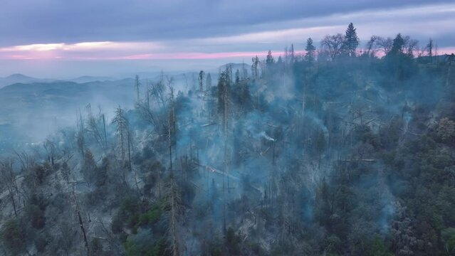Drone footage of picturesque sunrise over wildfire in mountainous landscape