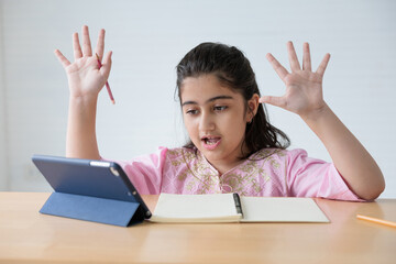muslim girl using a tablet computer and raised hand for say hello or goodbye pose on the table