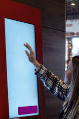 people choose and buy food at the self-service terminal in a cafe
