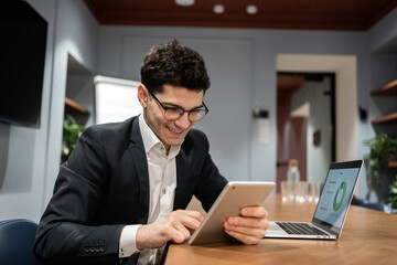 Manager with glasses in a business suit working office, using a laptop answering a client's email