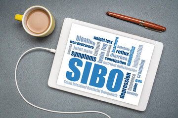 SIBO (small intestinal bacterial overgrowth) symptoms - word cloud on a digital tablet, flat lay...