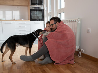 Couple under blanket in cold apartment trying to warm up.