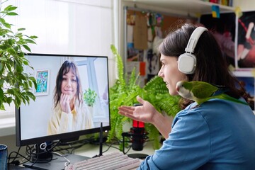 Online meeting of teenagers friends, guy with pet parrot at home talking to a female