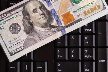100 dollar banknote on black computer keyboard