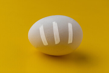a white egg with a crack, with tape applied to it, treatment and health care concept