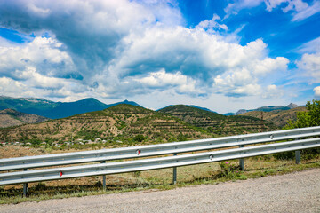 Fototapeta na wymiar An asphalt road against the backdrop of mountains and a stunningly beautiful sky with clouds. City district of Sudak, Republic of Crimea.