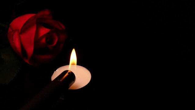 Roses and burning candles on black background as symbol mourning, memory or valentine day.