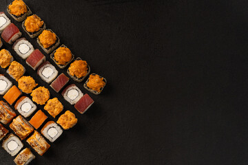 Japanese cuisine, set of fresh fish rolls on a black background with copy space