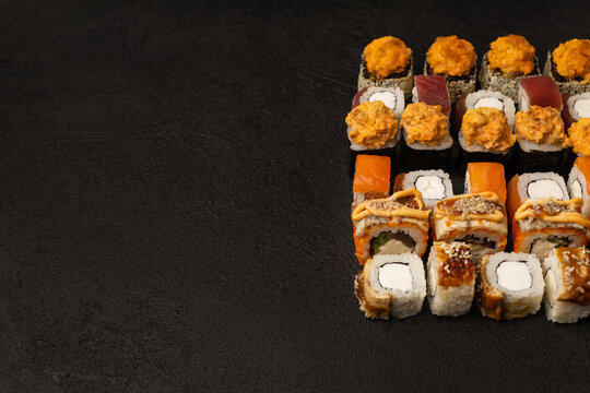 Japanese cuisine, set of fresh fish rolls on a black background with copy space