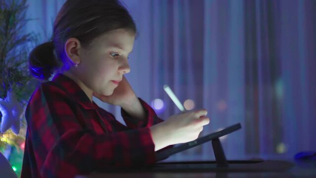 Teen girl is drawing or writing diary in room by tablet with digital pen